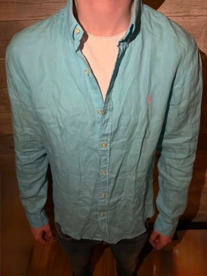 Ljusblå skjorta från Polo Ralph Lauren - Säljer en ljusblå skjorta från Polo Ralph Lauren med klassisk button-down krage och broderad logga på bröstet. Skjortan har långa ärmar, knappar framtill och är tillverkad i mjuk bomull. Perfekt för en clean och avslappnad stil.