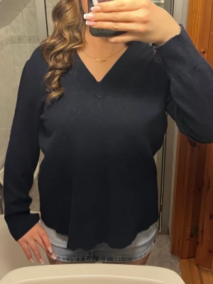 Marinblå stickad V-ringad tröja - Mysig marinblå stickad tröja med V-ringning och långa ärmar. Kommer ej till användning