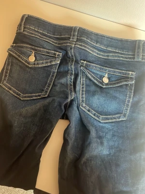 Mörkblå jeans  - Ett par mörkblå jeans med fina detaljer på bakfickorna. Inga defekter och använt fåtal gånger 