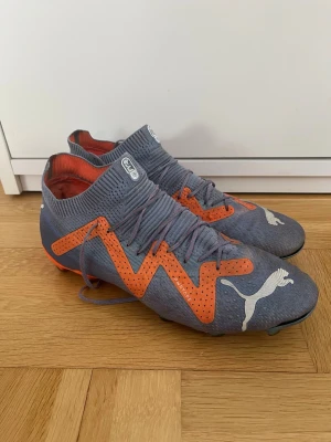 Puma Future Ultimate FG/AG Supercharge 42.5 - Original skor, Puma Future Ultimate FG/AG Supercharge fotbollsskor. Skorna är i använt skick och fullt fungerande. Dessa skor är till användning för både naturgräs och konstgräs. Storlek 42.5.