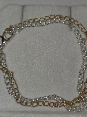 Tvåfärgat kedjearmband i rostfritt stål  - Snyggt armband med dubbla kedjor i både silver- och guldfärgad rostfritt stål. Armbandet har en klassisk karbinhake och stilren design som passar till många olika looks. Perfekt accessoar för att lyfta din outfit.