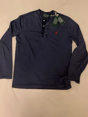 Henley tröja Ralph Lauren ny - Mörkblå långärmad henley-tröja från Polo Ralph Lauren i xs. Stor i storlek så passar snarare s. Aldrig använd (lappen kvar). Inköpt på boozt, ca 1300 i nypris. Skriv vid funderingar !