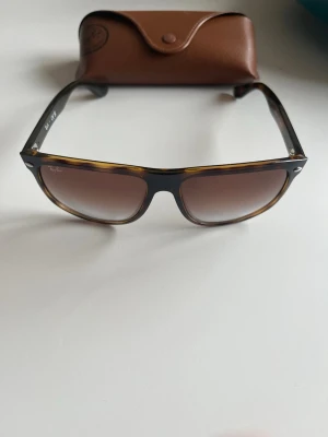 Rayban boyfriend solglasögon - Säljer ett par klassiska Ray-Ban solglasögon med brunmelerad båge och bruna tonade glas. Snygg retrostil och kommer med original brunt fodral. Perfekta för dig som vill ha en tidlös och trendig look. Rayban Havana, digitalt kvitto finns.