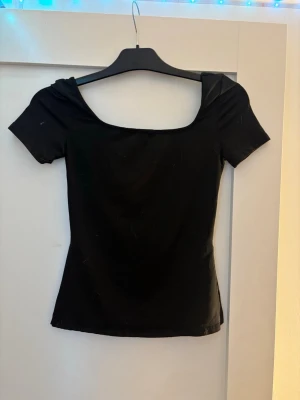Svart offshoulder topp - Snygg svart offshoulder topp med korta ärmar och en bred, fyrkantig ringning med slits i sidorna 