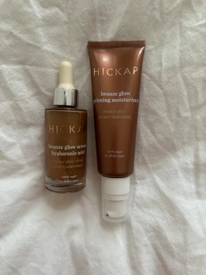 Hickap Bronze Glow Serum & Primer - Set med Hickap bronze glow serum med hyaluronsyra och bronze glow priming moisturizer. Båda produkterna är i bronsfärgade förpackningar och 100% veganska. Serumet kommer i glasflaska med pipett och primern i tub med pump. Endast testade1-2ggr