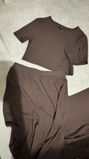 Brunt set - Ett set, ett par långa byxor och en tight T-shirt i brun färg. Ribbat. Aldrig använt.