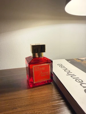 Baccarat Rouge 504 Eau de Parfum - En lyxig parfymflaska i röd glasdesign med guldfärgat lock från Mason. Flaskan har en fyrkantig form och etiketten är röd med guldfärgade detaljer. Doften är Eau de Parfum och flaskan ger ett exklusivt intryck, perfekt för dig som gillar eleganta och trendiga parfymer.