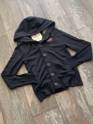 Hollister cardigan  - Säljer en riktig snygg Hollister Cardigan Hoodie. Denna är väldigt välkänd och många som söker. Den är sällsynt och snygg. Skicket är 10/10. Storlek är S. Priset kommer ligga på 699kr.