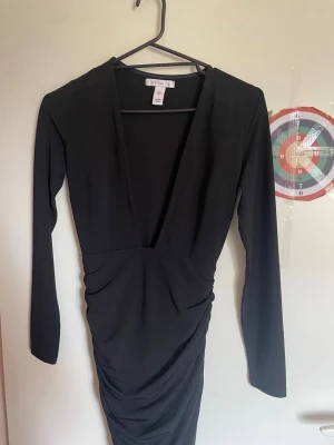 Svart långärmad klänning Notion 1.3 - Säljer en svart långärmad klänning från Notion 1.3 i storlek XS. Klänningen har djup v-ringning och snygg rynkning i midjan. Sitter åt mot kroppen perfekt och ass snyggt. Perfekt för dig som gillar stilrena och trendiga plagg.