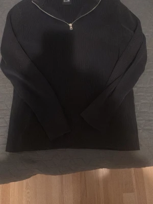 Svart stickad halvzip från Only & Sons - Snygg svart stickad tröja från Only & Sons med halv dragkedja vid halsen. Tröjan har ribbad struktur, lång ärm och en stilren look som passar perfekt till alla klädstilar.