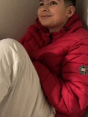 Röd pufferjacka  - Säljer en snygg röd pufferjacka  med klassisk quiltad design och hög krage. Jackan har en rund Moncler-logga på ärmen och dragkedja framtill. Perfekt för kalla vinterdagar och riktigt trendig stil.