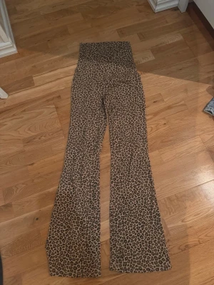Leopardmönstrade utsvängda leggings - Säljer ett par leopardmönstrade leggings med hög midja och utsvängda ben. De är i stretchigt material och har en cool och trendig look som verkligen sticker ut. Perfekt för dig som gillar att synas och vill ha något unikt i garderoben.