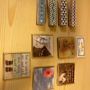 Dekorativa magneter och klädnypor - Säljer ett set med fyra stora klädnypor i trä med magneter på baksidan och fem dekorativa kylskåpsmagneter med olika citat och motiv.