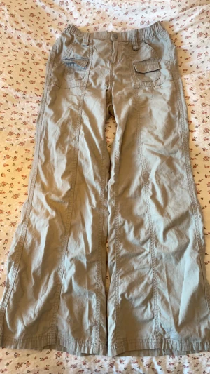 Gråa cargobyxor med fickor - Stilrena gråa cargobyxor med flera praktiska fickor framtill. Byxorna är stretchiga och är tillverkade i ett mjukt bomullstyg. Finns få tecken på användning, det enda är nog att den lilla fickan han fastat uppåt men det är något man förmodligen kan fixa med strykjärn!! 🩶