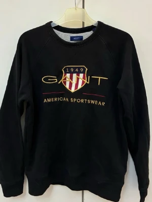 Svart sweatshirt från GANT - Gant tjocktröja med guldiga detaljer. Sitter som storlek S/XS.