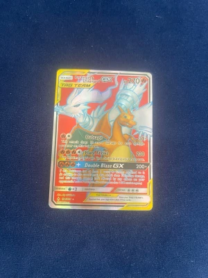 Pokémonkort Reshiram & Charizard GX - Säljer ett Pokémonkort med Reshiram & Charizard GX TAG TEAM. Kortet har en färgstark design med röd, gul och vit bakgrund och holografiska detaljer. Perfekt för samlare eller dig som vill boosta din lek med en kraftfull GX-kombination.