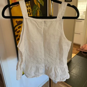 Vit broderad linnetopp från hm - Söt vit linnetopp från hm i storlek 34. Toppen har breda axelband, broderade detaljer och lätt volang nedtill. Perfekt för varma dagar och ger en fräsch och somrig look.