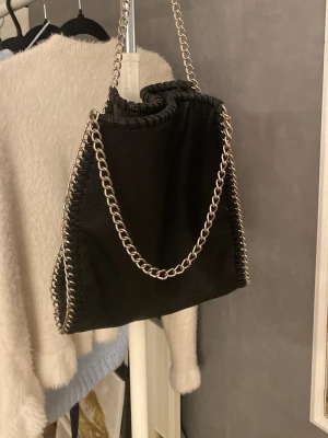 Svart kedjeväska från Gina Tricot - Super snygg handväska/axelremsväska från Gina Tricot i fejkläder. Den har blivit använd 2-3 gånger och ser ny ut. Säljer då jag köpt en annan väska. Kostade 350kr när jag köpte den. Pris kan diskuteras!💕