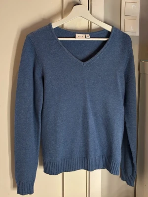 Blå stickad tröja med v-ringning från Vila - Snygg blå stickad tröja från Vila med v-ringad hals och ribbade muddar vid ärmslut och nederkant. Perfekt för lager-på-lager och enkel att matcha med jeans eller kjol. Materialet är mjukt och behagligt, och tröjan har en klassisk, rak passform. Hör av dig vid frågor!🥰🤍Nypris 399kr✨