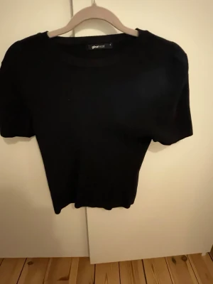 Svart croppad topp från Gina Tricot - En enkel och stilren svart croppad topp från Gina Tricot. Toppen har rund halsringning och korta ärmar. Perfekt att matcha med höga jeans eller kjol för en clean look.