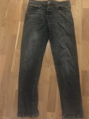 Svarta raka jeans från Jack and Jones - Köptes för 800kr. Säljer ett par svarta jeans med raka ben. Jeansen har klassisk femficksmodell, knappgylf och kontrastsömmar. Perfekta för en avslappnad och stilren look. Storlek 33/34