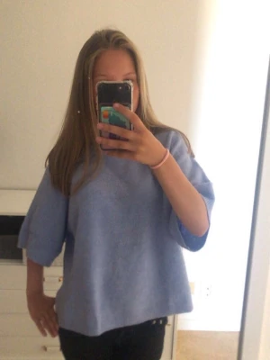Ljusblå oversized topp med kort ärm - En ljusblå oversized topp med korta, vida ärmar och rak passform. Toppen har en enkel och clean design utan synliga detaljer eller mönster, vilket gör den lätt att styla till olika outfits. Materialet ser mjukt och bekvämt ut, perfekt för en avslappnad look.🩵