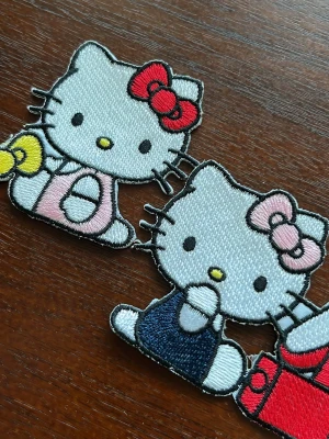 Två stycken Hello Kitty patches  - Ena är 6x7 cm, andra är 5x5,5 cm. Man behöver stryka på dem på plagget så att klistret smälter för att de fastna! 