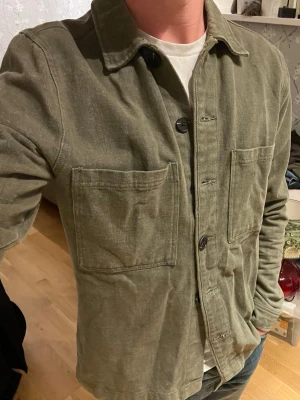 Grön Studio Total Overshirt - Overshirt ifrån studio total.  Mycket bra skick. Dock har knappen längst ned lossnat, men medföljer. Så det går lätt att sy på  Sitter enligt storlek (s)
