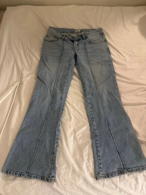 Ljusblå bootcut jeans - Säljer ett par ljusblå bootcut jeans med låg midja och klassiska fem fickor. Jeansen har utsvängda ben och är tillverkade i denim. Perfekta för dig som gillar en retro och avslappnad stil.