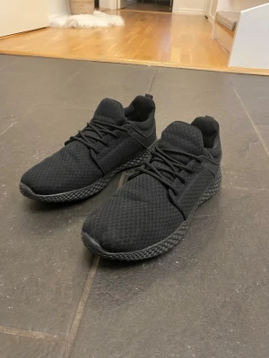 Helvita mesh sneakers med svart sula - Snygga helsvarta sneakers med mesh-ovandel och matchande svart sula. Skorna har lågt skaft, klassisk snörning och en sportig, modern look. Perfekta för dig som gillar stilrena och bekväma sneakers till vardags.