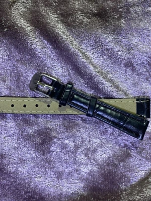 Svart klockarmband i läderimitation - Snyggt svart klockarmband i läderimitation med krokodilpräglad yta och silvrigt spänne. Armbandet har flera hål för justerbar passform och en klassisk design som passar de flesta klockor. Finns stlk kvar 12,14,16,18,20,22 mm kvar, helt ny 