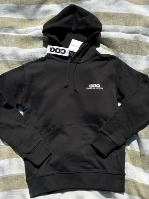 Hoodie Comme des Garçons CDG - Svart hoodie från Comme des Garçons, köpt från street dover market i London. Säljer eftersom att den är för liten | Aldrig använd | Tagsen finns kvar
