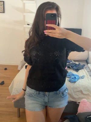 Svart blus med ihåligt mönster - Säljer en svart blus med korta ärmar Blusen har en normal passform och är tillverkad i ett lätt material som passar perfekt till sommaren.
