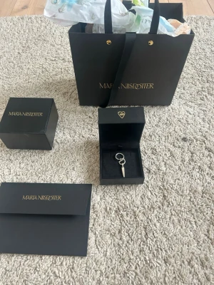 Silverörhänge Maria Nilsdotter Spade - Säljer ett coolt örhänge från Maria Nilsdotter i äkta silver. Örhänget har en unik design som liknar en liten spade med spetsig form och ringfäste. Perfekt för dig som gillar statement-smycken och vill sticka ut lite extra.