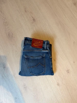 Blå jeans från Jacob Cohen - Snygga blå jeans från Jacob Cohen med klassisk femficksmodell och kontrastsömmar. Jeansen har en rod patch med logga bak och silverfärgade nitar. Perfekta för dig som gillar stilrena och tidlösa jeans i denim.