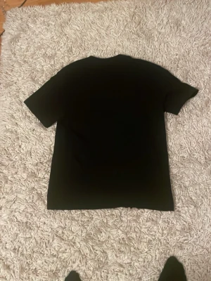 Svart t-shirt från Polo Ralph Lauren - Snygg svart t-shirt från Polo Ralph Lauren med klassisk passform och liten vit logga broderad på bröstet. Tillverkad i mjuk bomull och har rund hals samt korta ärmar. Perfekt basplagg för alla tillfällen.