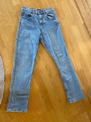 Ljusblå raka jeans från Lee - Säljer ett par ljusblå raka jeans från Lee med klassisk femficksmodell och hög midja. Jeansen har Lee-lapp bak i midjan och är tillverkade i ett mjukt denimtyg. Perfekta för en avslappnad och trendig look.