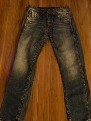 Blå raka jeans med slitningar - Snygga blå jeans med raka ben och slitna detaljer på låren och knäna. Klassisk femficksmodell med knapp och dragkedja. Perfekta för en avslappnad och trendig look.