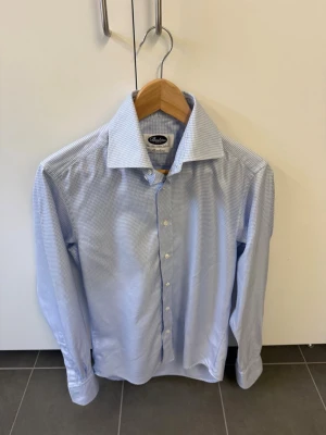Blåvit skjorta från Stenströms, stl 40 - Snygg blåvit skjorta från Stenströms i slim fit-modell. Skjortan har ett diskret rutigt mönster, klassisk krage och knäppning framtill. Tillverkad i 100% bomull för en skön känsla. Perfekt för dig som gillar stilrena och klassiska plagg.