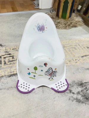 Vit potta med zebramotiv - Söt vit potta i plast med lila detaljer och motiv av zebra, träd och ballong framtill. Pottan har hög rygg för extra stöd och halkskydd på fötterna. Perfekt för småbarn som ska börja potträna.