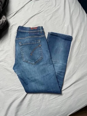 dondup jeans 32 - Säljer ett par klassiska blå jeans i rak modell. Jeansen har fem fickor, snygga kontrastsömmar och är tillverkade i denim med en lätt tvättad look. Perfekta för dig som gillar en enkel och tidlös stil.
