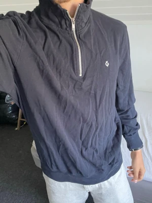 Svart halfzip tröja från C&A - Svart långärmad halfzip tröja från C&A Flex On the go. Tröjan har hög krage med dragkedja och en liten broderad logga på bröstet. Perfekt för en avslappnad och stilren look.