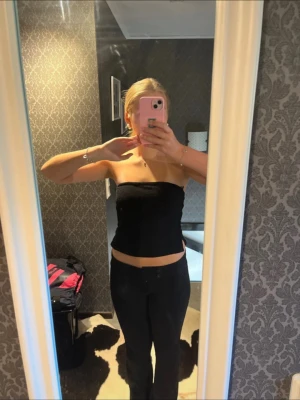 Svart tubtopp med snygg passform - Svart axelbandslös tubtopp med tight passform och rak skärning upptill. Toppen har en enkel och stilren design, perfekt att matcha med olika outfits. Materialet känns mjukt och stretchigt för en bekväm känsla.