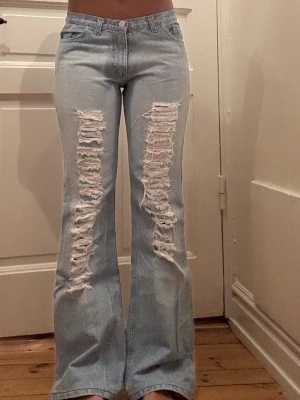 Ljusblå bootcut jeans med hål/slitningar - Säljer ett par ljusblå Levi's jeans med bootcut passform och stora slitningar framtill på båda benen. Vekrligen så fina och köpta på Urban outiftters. Midjemåttet är 37 cm Innerbenslängden är 78!