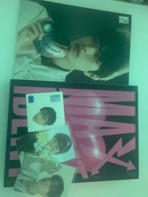K-pop album MAXIDENT med photocard - Säljer ett K-pop album 'MAXIDENT' från Stray Kids. Paketet innehåller albumbox, fotobok med svart och rosa omslag samt flera exklusiva photocard med medlemmar från gruppen. Perfekt för samlare och fans av K-pop. Albumet har en modern och färgstark design.