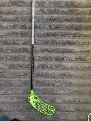 Unihoc innebandyklubba svart/grön - Säljer en innebandyklubba från Unihoc med svart skaft och grön blad. Skaftet har detaljer i grönt och vitt samt ett grepp i ljusgrått med mönster. Bladet är i plast med ett öppet rutmönster för lättare bollkontroll.