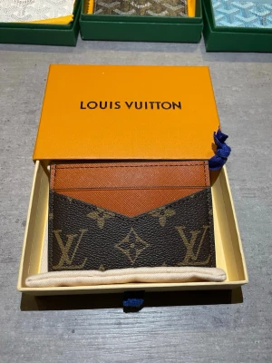  monogram korthållare - Snygg korthållare i klassiskt brunt monogrammönster med detaljer i cognacsfärgat läder. Slimmad och stilren design med flera kortfack. Perfekt accessoar för dig som gillar lyxiga detaljer och tidlös stil.