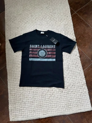 Mörkblå Saint Laurent t-shirt med tryck - Säljer denna tvärfeta eftertraktade saint Laurent t-shirten för ett fantastiskt pris som går att diskutera. Skriv vid frågor eller funderingar!🤩