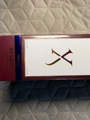 Xerjoff Soprano Eau de Parfum 100ml - Lyxig parfym från Xerjoff i doften Soprano. Kommer i en elegant vinröd och vit förpackning med gulddetaljer och stor logotyp på framsidan. Flaskan rymmer 100 ml och är perfekt för dig som gillar exklusiva och unika dofter.