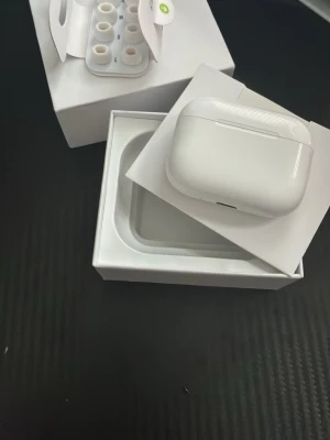 Vita trådlösa in-ear hörlurar - Säljer ett par vita trådlösa in-ear hörlurar från Apple med laddningsetui. Hörlurarna har en stilren och kompakt design i blank plast och levereras sopade i originalförpackning med extra silikontoppar i olika storlekar. Perfekta för musik, poddar och samtal. Dem är inte original 